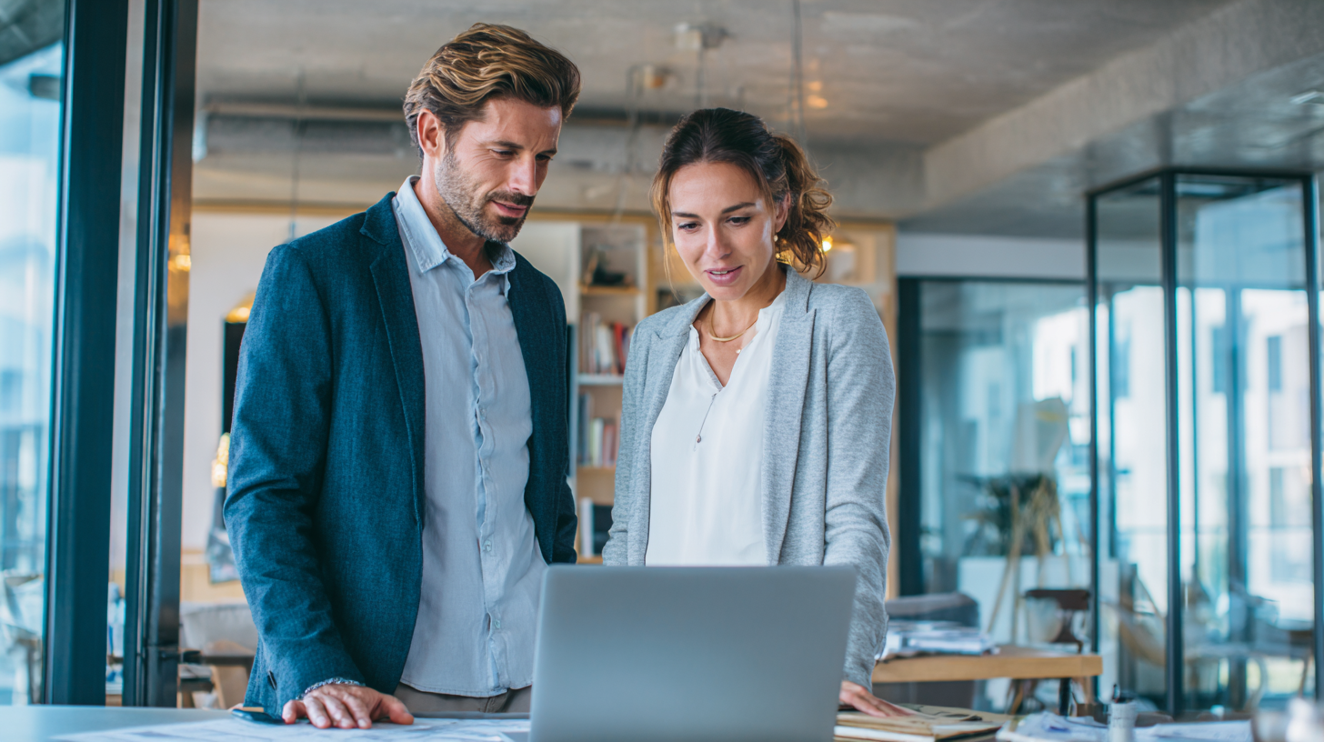 Two real estate agents standing next to a laptop and discussing their schema markeup for SEO.