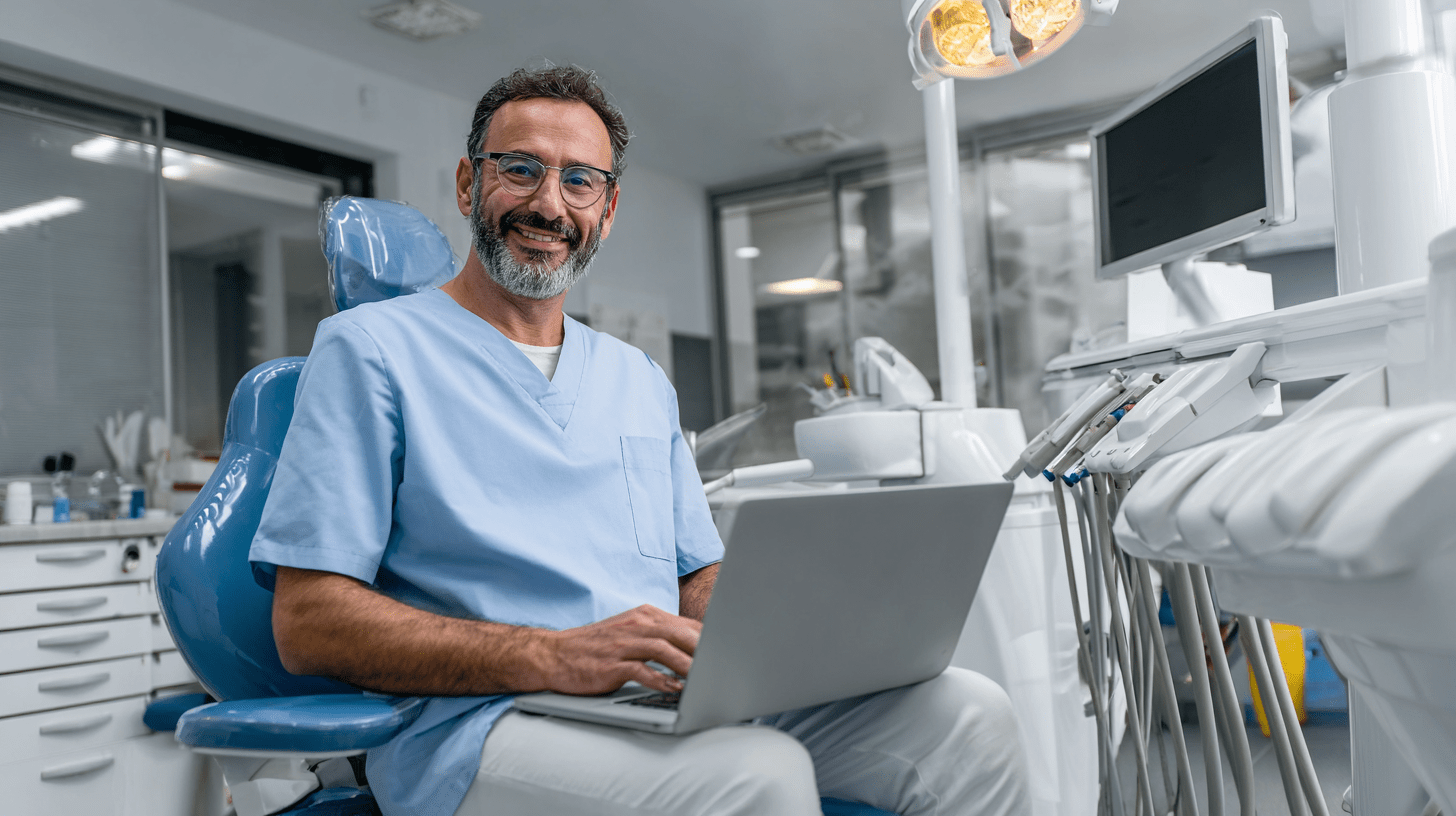 A dentist in his clinic working on a laptop on his dental SEO.